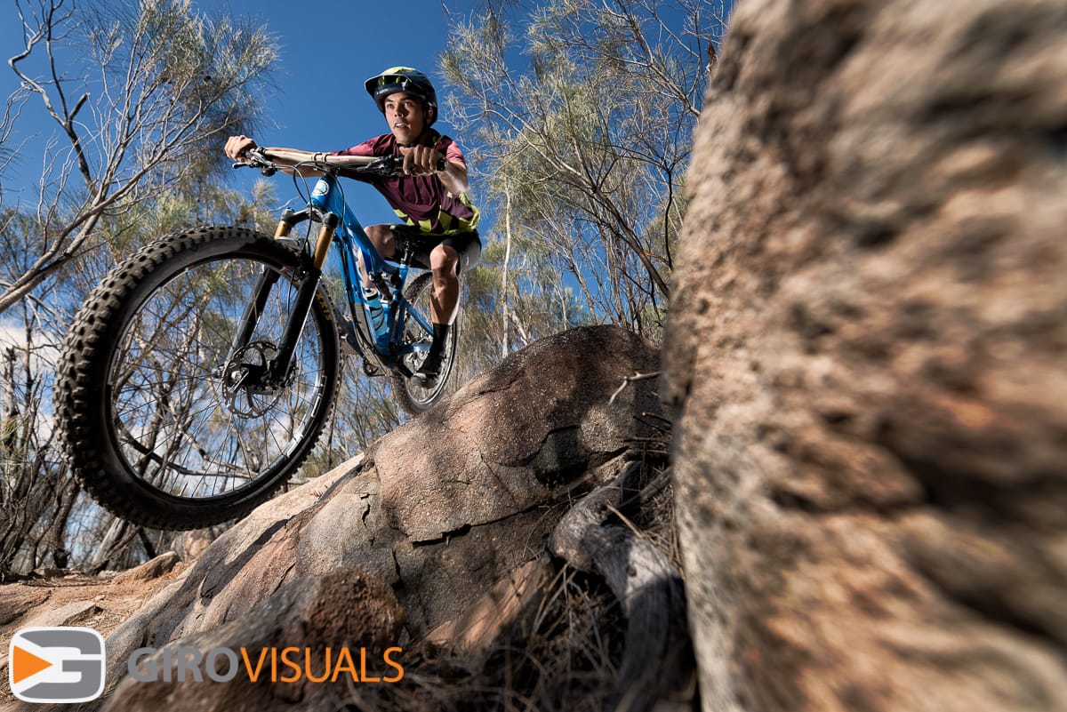 Enduro mountain bike rider flies past the camera coming close to making contact as he takes the inside line.